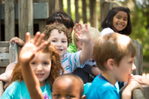 Magnolia Speech School kids gather in the playground and wave to the camera.